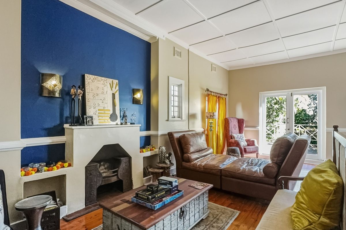 A living room featuring a prominent fireplace with a blue accent wall, hardwood floors, and access to an outdoor area through french doors.
