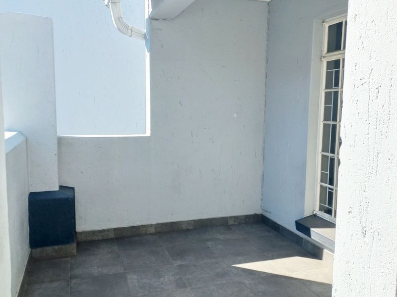 A covered balcony area featuring tiled flooring and a security gate, providing a functional outdoor space for the townhouse.