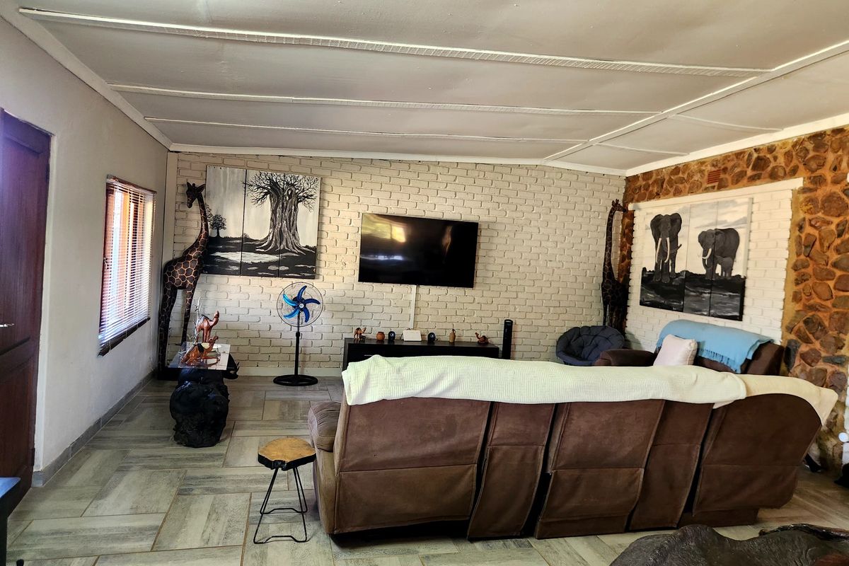 A living room featuring a combination of painted brick and natural stone walls, tiled flooring, and a panelled ceiling.
