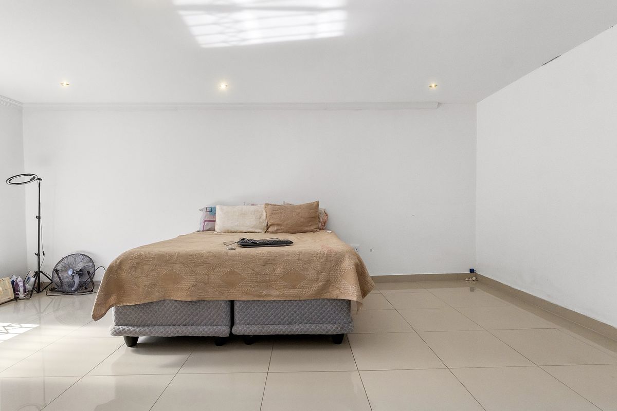 A spacious bedroom featuring neutral tiled flooring and recessed downlighting, offering a clean and simple canvas for personalization.