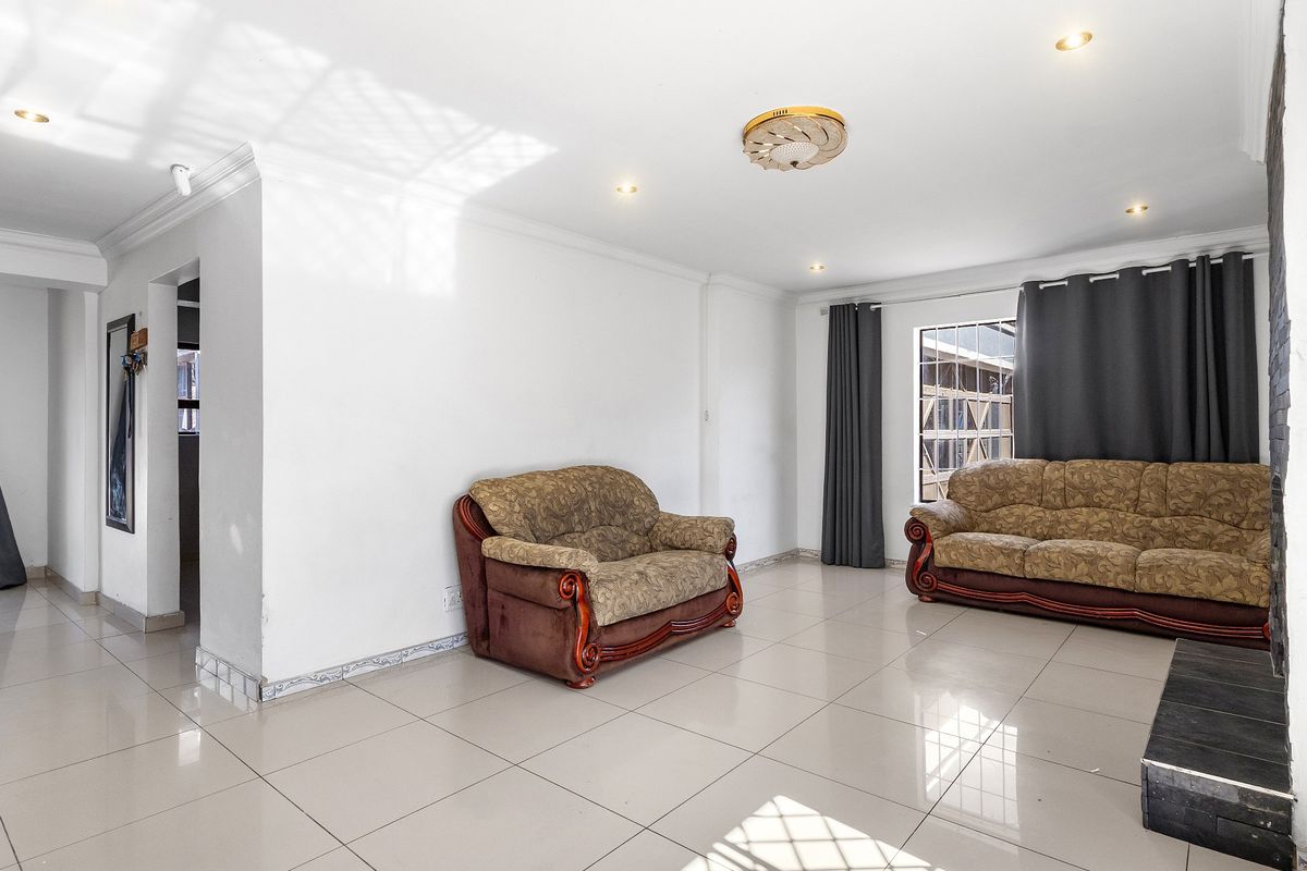 Spacious living room featuring large format floor tiles, recessed downlighting, and a stone-clad feature wall, offering a bright and open living space.