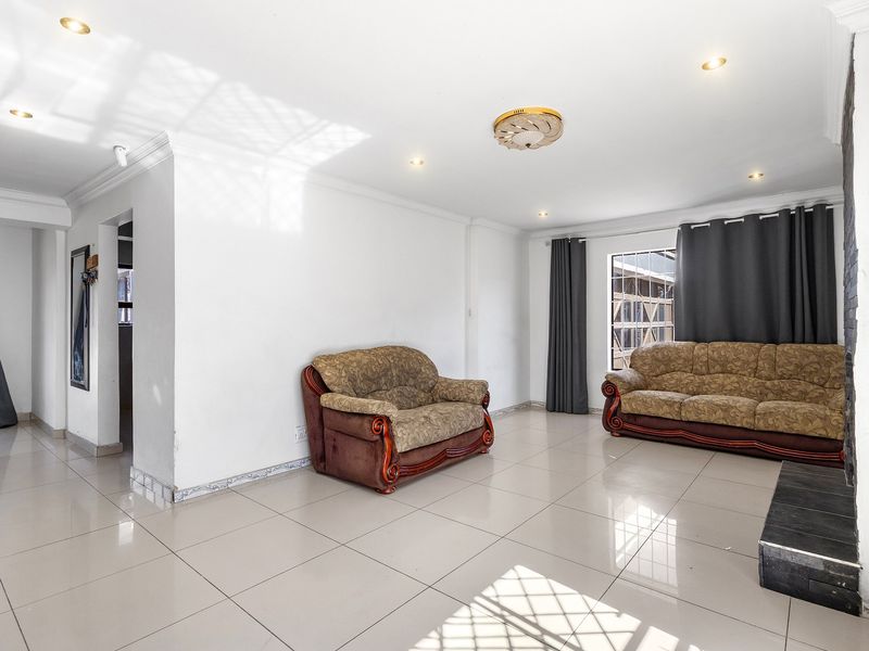 Spacious living room featuring large format floor tiles, recessed downlighting, and a stone-clad feature wall, offering a bright and open living space.
