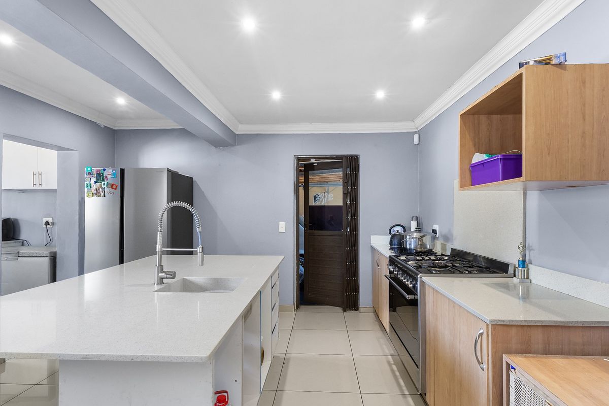 Modern kitchen featuring a central island with stone countertops, gas stove, ample cabinetry, and recessed lighting, providing a functional and well-lit cooking space.