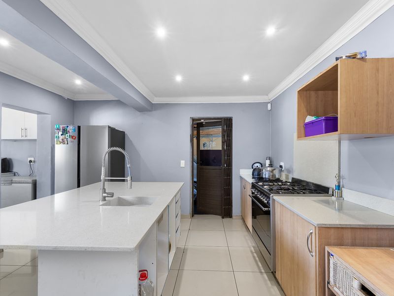 Modern kitchen featuring a central island with stone countertops, gas stove, ample cabinetry, and recessed lighting, providing a functional and well-lit cooking space.