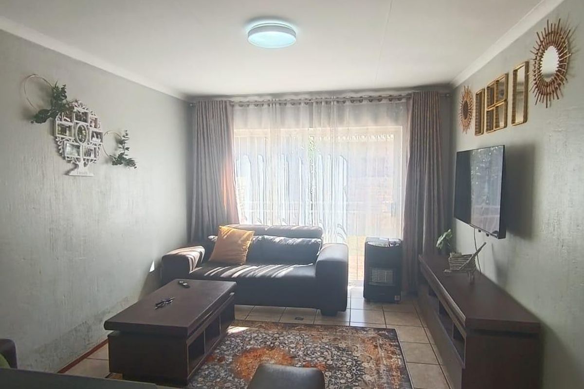 A comfortable living room featuring tiled flooring, neutral wall finishes, and a sliding door providing access to the exterior.