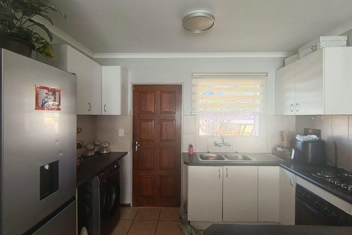 Functional kitchen featuring white cabinetry, dark countertops, a double basin sink, integrated hob and oven, and tiled flooring.