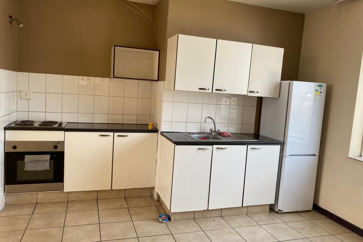 A functional kitchen featuring white cabinetry, tiled backsplash, built-in oven, electric hob, and tiled flooring, offering a blank canvas for potential updates.