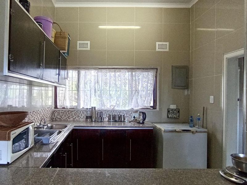 A functional kitchen featuring granite countertops, dark cabinetry, and fully tiled walls, providing a practical workspace with ample storage.