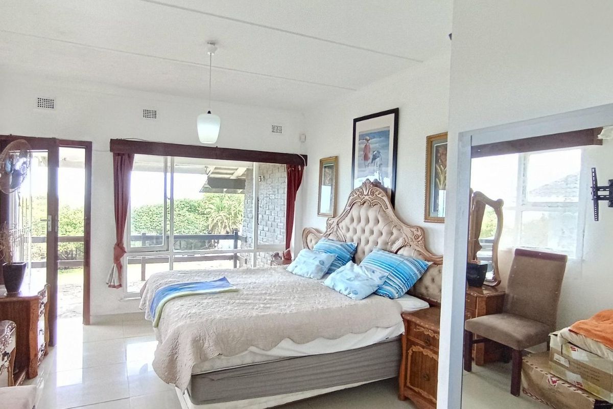 Spacious bedroom featuring tiled flooring, a pendant light, and a large sliding glass door providing direct access to an outdoor patio area.