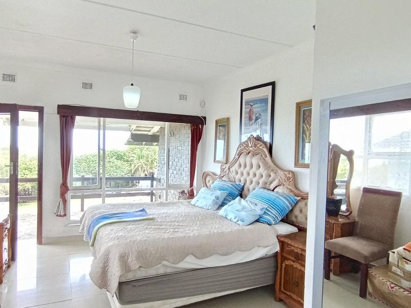 Spacious bedroom featuring tiled flooring, a pendant light, and a large sliding glass door providing direct access to an outdoor patio area.