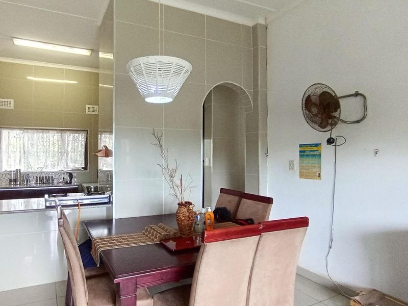 Open plan dining area featuring tiled flooring and an archway leading to a kitchen with granite countertops and tiled wall finishes.