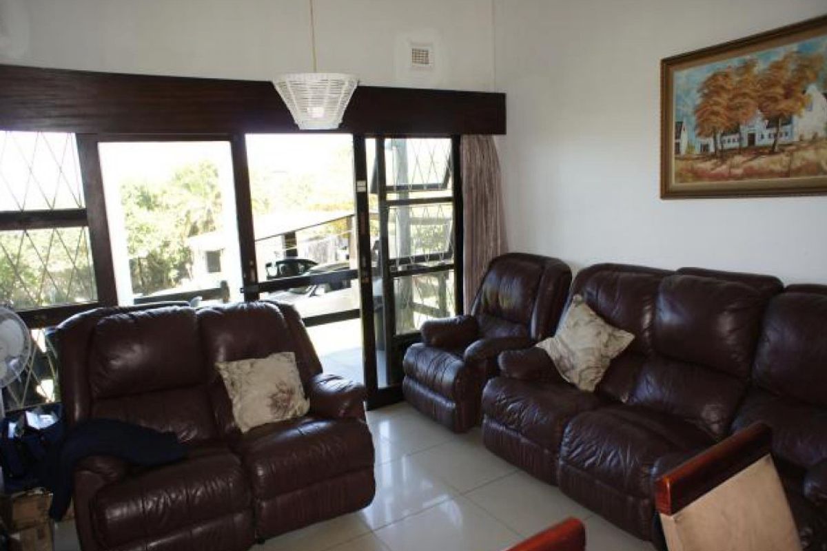 A living room featuring large sliding glass doors that provide natural light and access to the exterior, complemented by neutral tiled flooring.