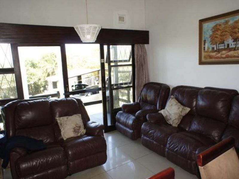 A living room featuring large sliding glass doors that provide natural light and access to the exterior, complemented by neutral tiled flooring.