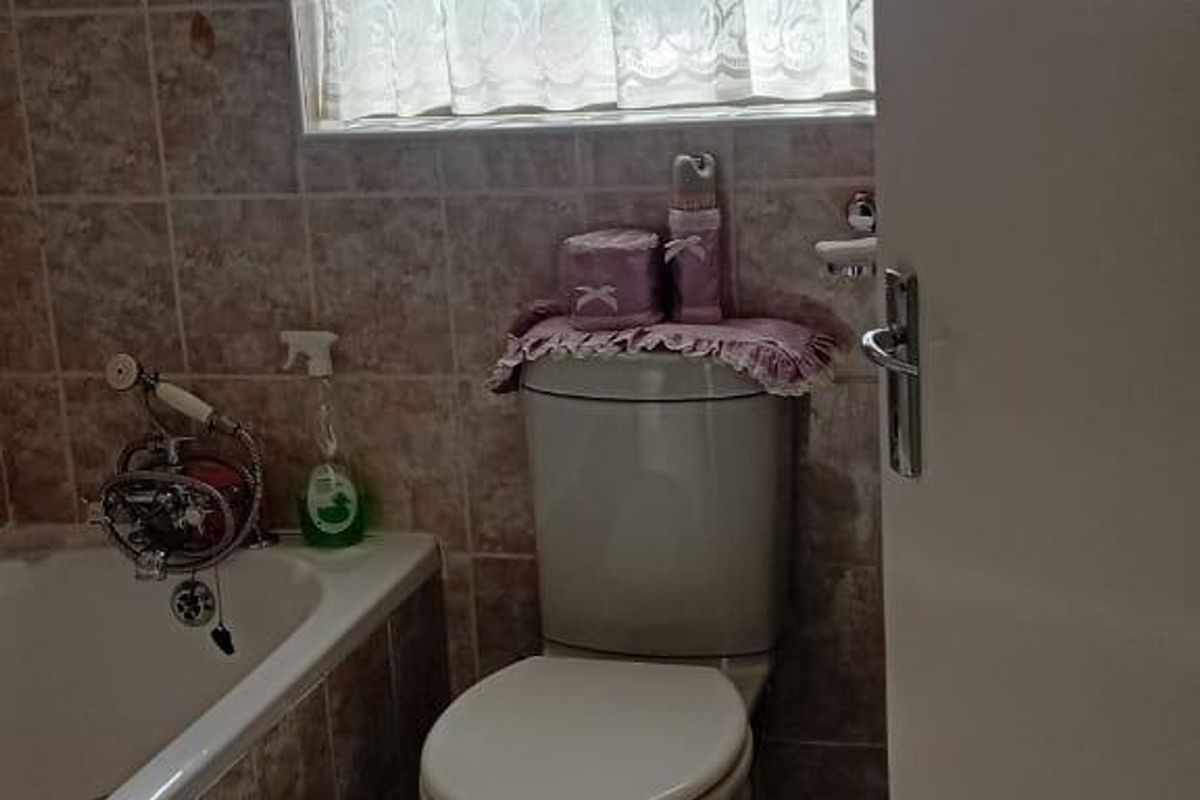 A compact bathroom featuring a bathtub, toilet, and tiled finishes. The space would benefit from modernization to improve its dated aesthetic.