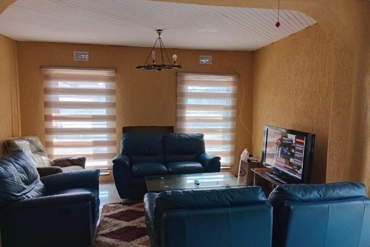 A living room featuring textured walls, a tongue and groove ceiling, and dual windows with fitted roller blinds.