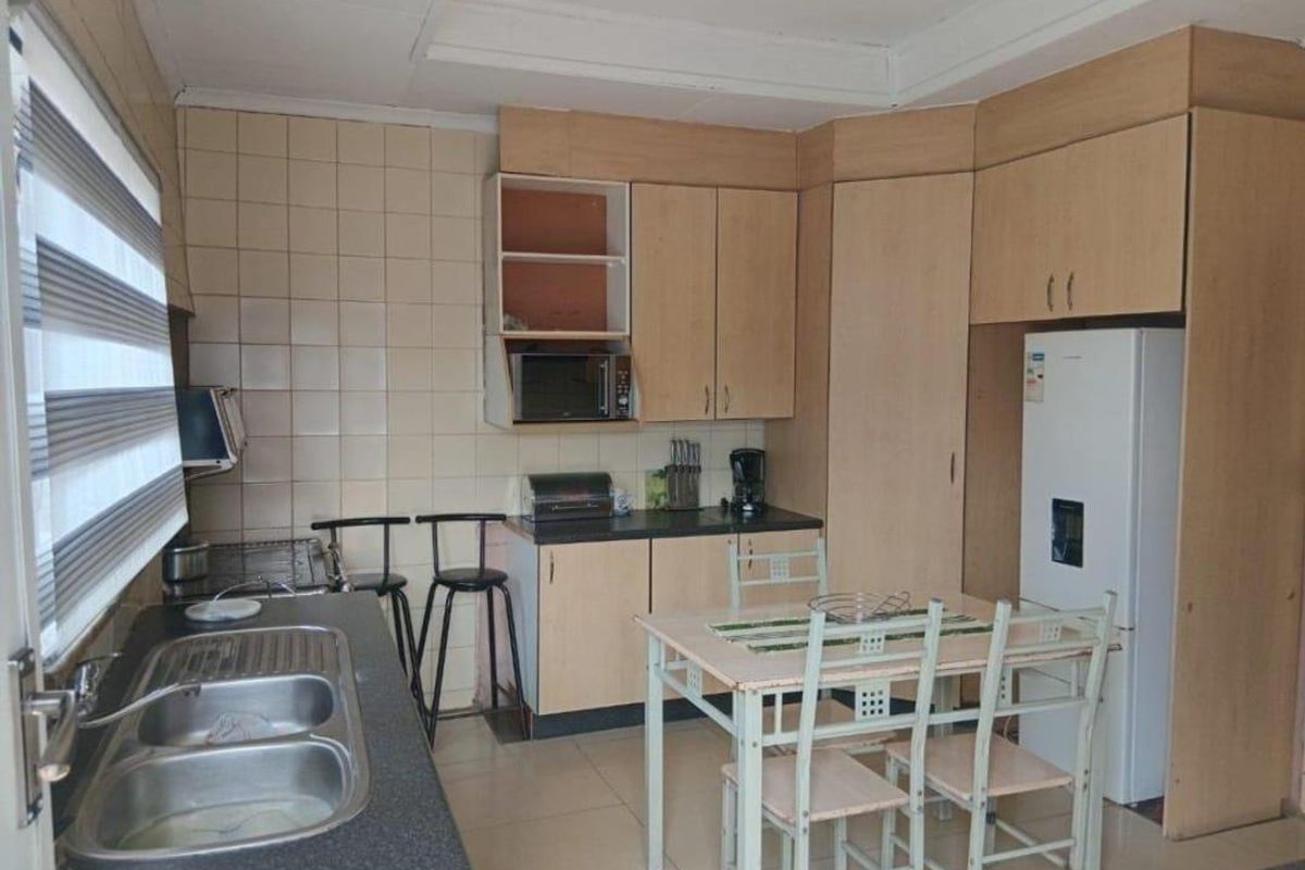 A functional kitchen featuring laminate cabinetry, a double bowl stainless steel sink, and tiled splashbacks, offering a practical layout for daily meal preparation.