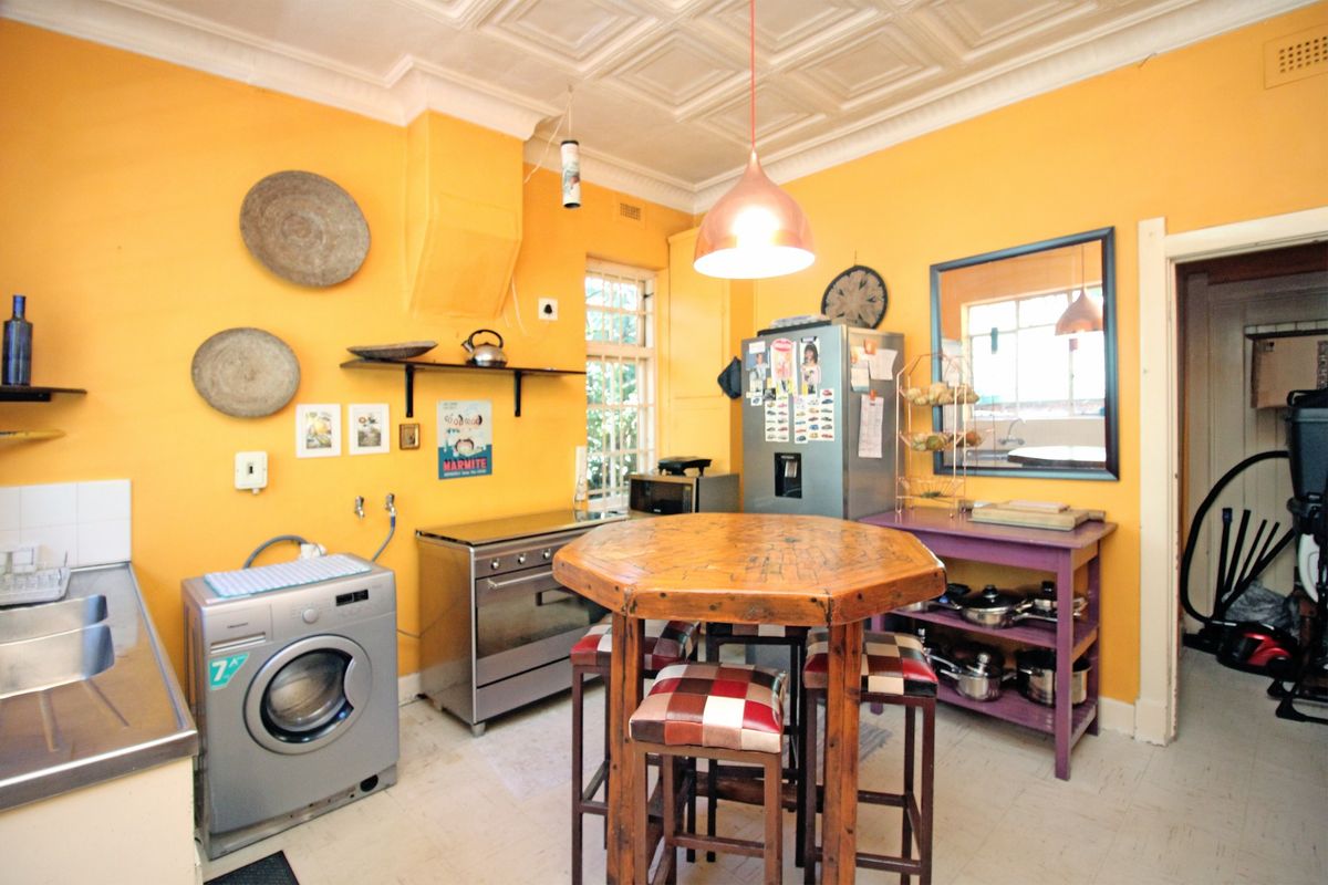 A dated kitchen featuring bright yellow walls, a tiled ceiling, and a freestanding oven, offering significant potential for a modern renovation.