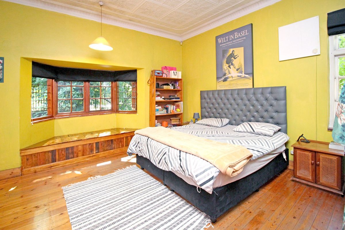 Spacious bedroom featuring original timber flooring, a charming bay window with built-in seating, and an ornate pressed metal ceiling.