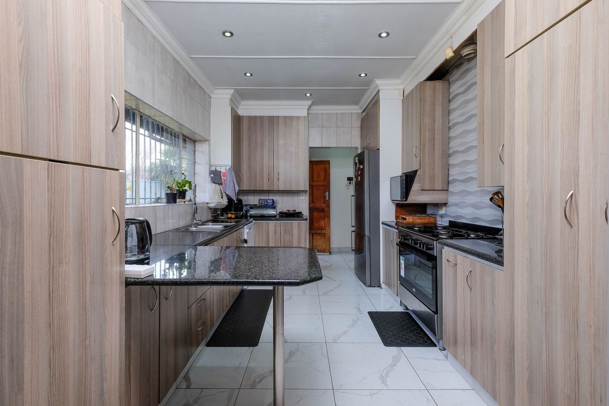Modern kitchen featuring granite countertops, ample built-in cabinetry, stainless steel appliances, and tiled flooring with a functional layout.