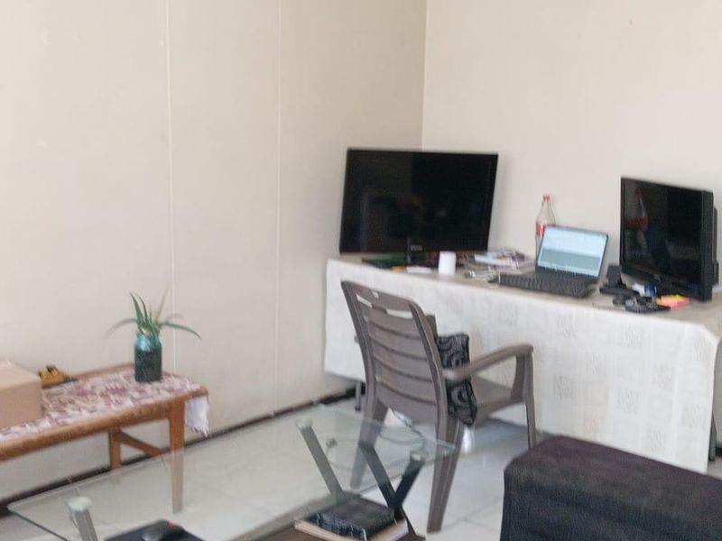 A living room area featuring tiled flooring and neutral wall finishes, providing a functional space for relaxation or home office use.