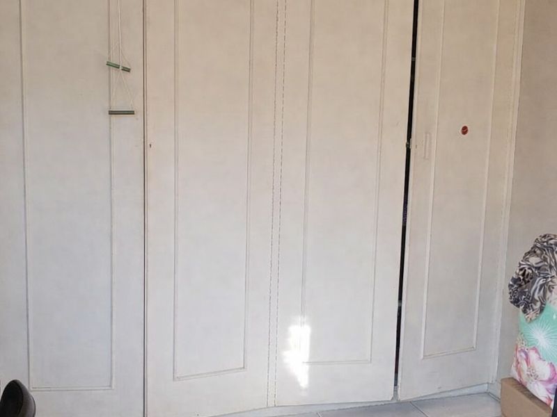 Bedroom featuring built-in wardrobes with white panelled doors and light-colored tiled flooring.