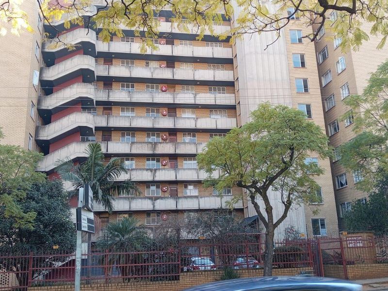 Exterior view of a multi-story apartment building featuring a brick facade, external fire escape staircase, and private balconies.