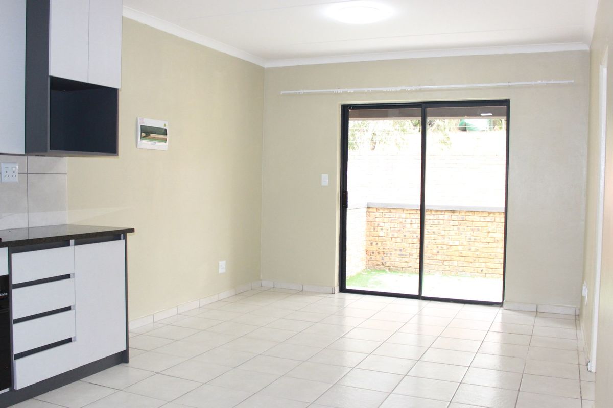 Open-plan living area featuring tiled floors, modern kitchen cabinetry with built-in oven, and sliding glass doors leading to an outdoor space.
