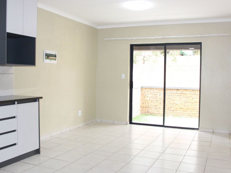Open-plan living area featuring tiled floors, modern kitchen cabinetry with built-in oven, and sliding glass doors leading to an outdoor space.