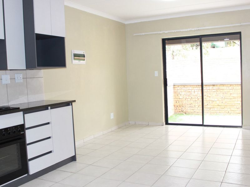 Open-plan kitchen and living area featuring modern cabinetry, built-in oven and hob, tiled flooring, and sliding door access to the exterior.