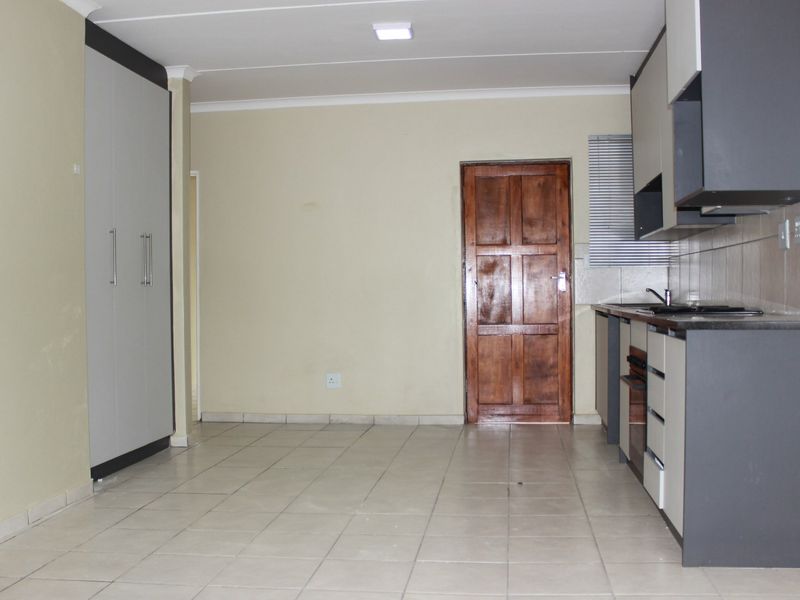 An open-plan living and kitchen area featuring tiled flooring, built-in cabinetry, and a functional kitchen layout with integrated appliances.