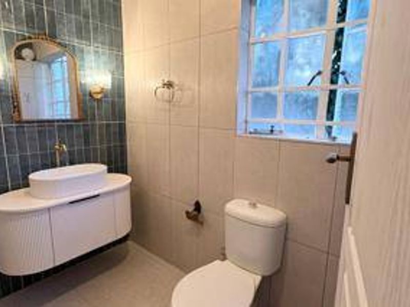 A modern bathroom featuring a stylish wall-mounted vanity with a vessel sink, a tiled feature wall, and a clean, functional layout.