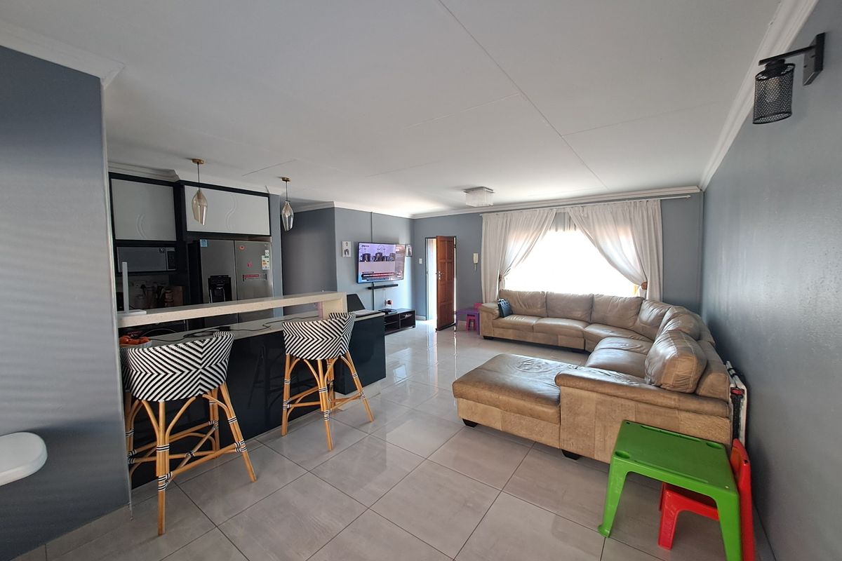 An open-plan living and kitchen area featuring tiled flooring, a breakfast bar, and modern cabinetry, creating a functional and connected living space.