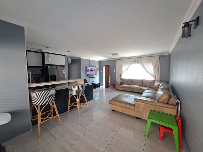 An open-plan living and kitchen area featuring tiled flooring, a breakfast bar, and modern cabinetry, creating a functional and connected living space.