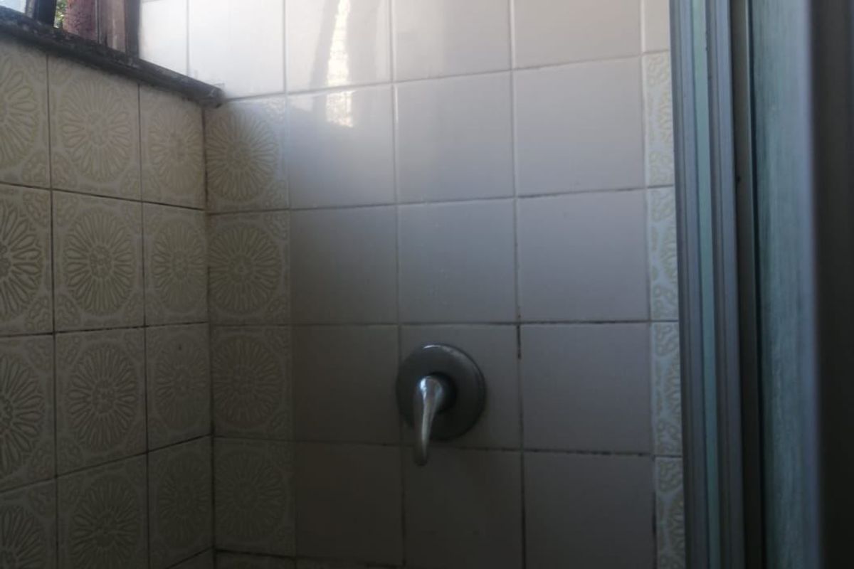 A compact shower enclosure featuring dated ceramic wall tiles and standard chrome shower fixtures.