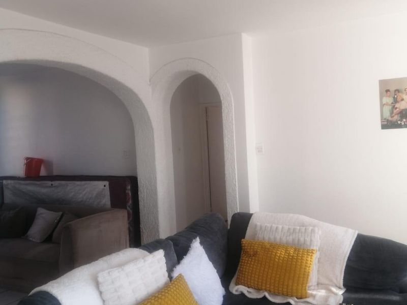 Living room area featuring distinctive arched architectural doorways and a ceiling fan, providing a classic layout with potential for modern updates.