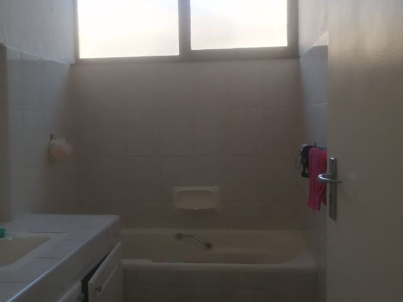 A functional bathroom featuring a built-in bathtub, tiled finishes, and a vanity cabinet. The space is ready for modernization and cosmetic updates.
