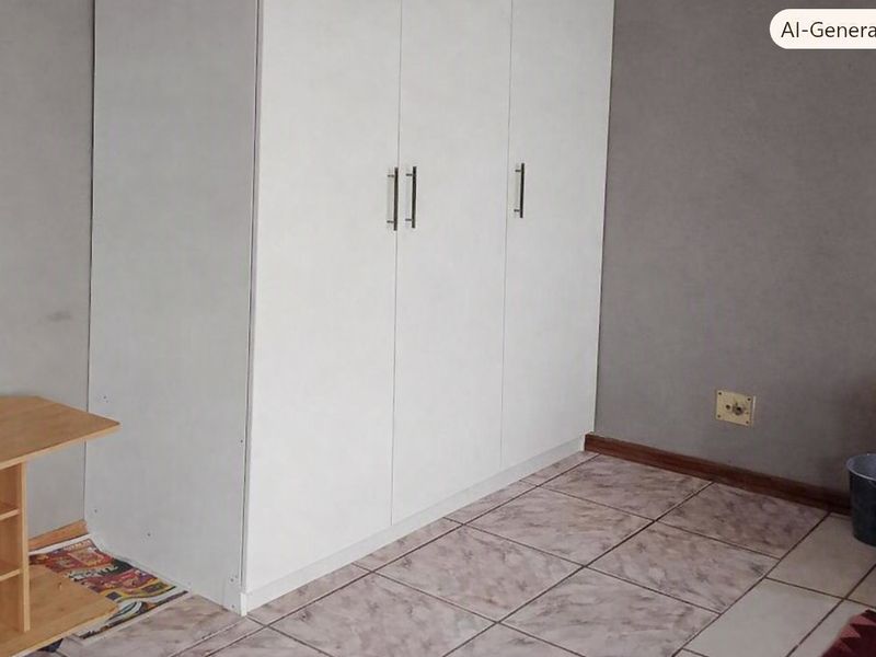 A bedroom featuring a built-in white wardrobe, tiled flooring, and neutral grey walls.