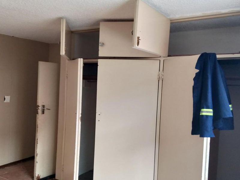 A bedroom featuring built-in cupboards with visible wear and tear, requiring maintenance or replacement to restore functionality and aesthetic appeal.
