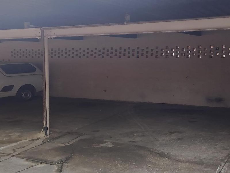 A covered parking garage area featuring concrete flooring and breeze block ventilation walls.