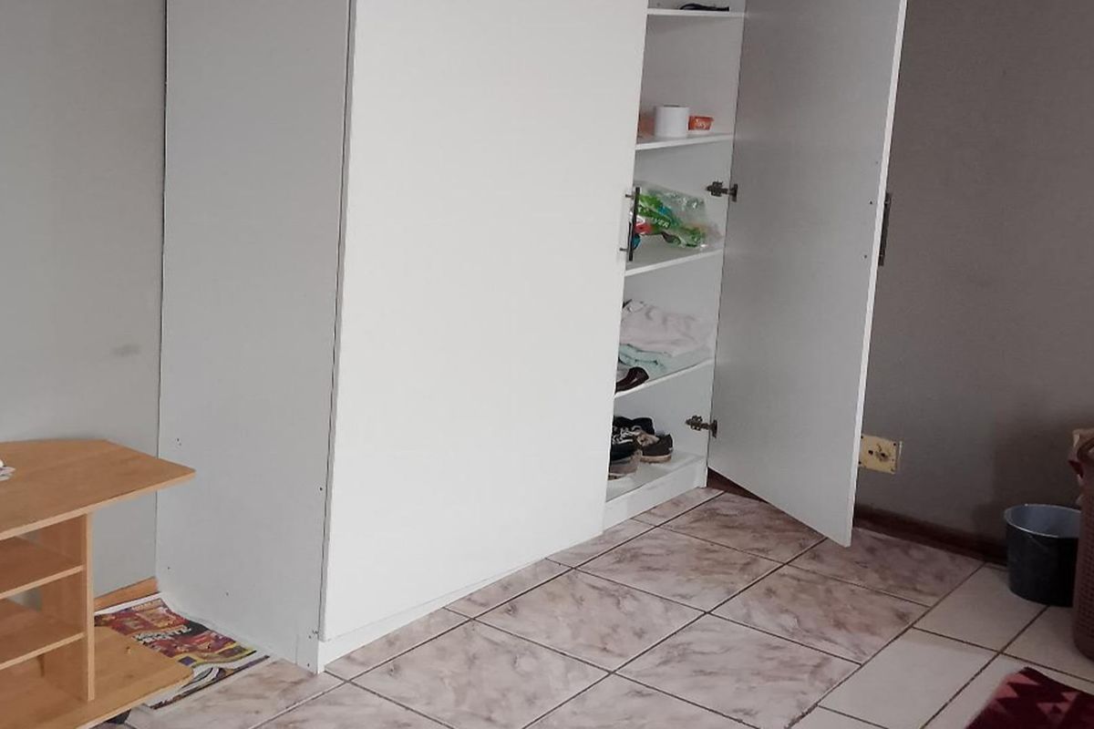 A bedroom featuring tiled flooring and a built-in white wardrobe, requiring minor cosmetic updates to improve the overall aesthetic.