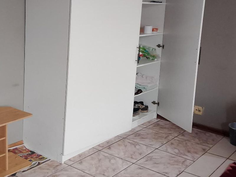 A bedroom featuring tiled flooring and a built-in white wardrobe, requiring minor cosmetic updates to improve the overall aesthetic.