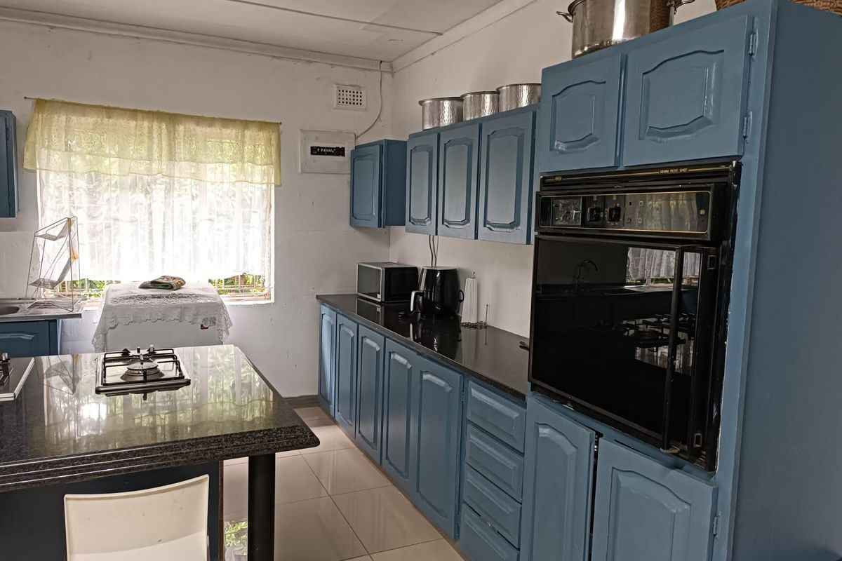A functional kitchen featuring blue built-in cabinetry, granite countertops, a gas hob, and a built-in oven with tiled flooring throughout.