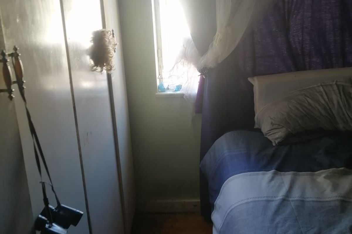 A compact bedroom featuring built-in cupboards and timber flooring, requiring minor cosmetic updates to improve the overall finish.