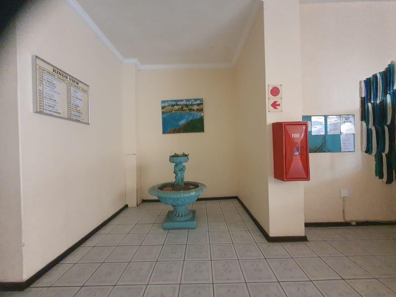 A functional apartment building entrance lobby featuring tiled flooring, a fire hose reel, and a building directory board.