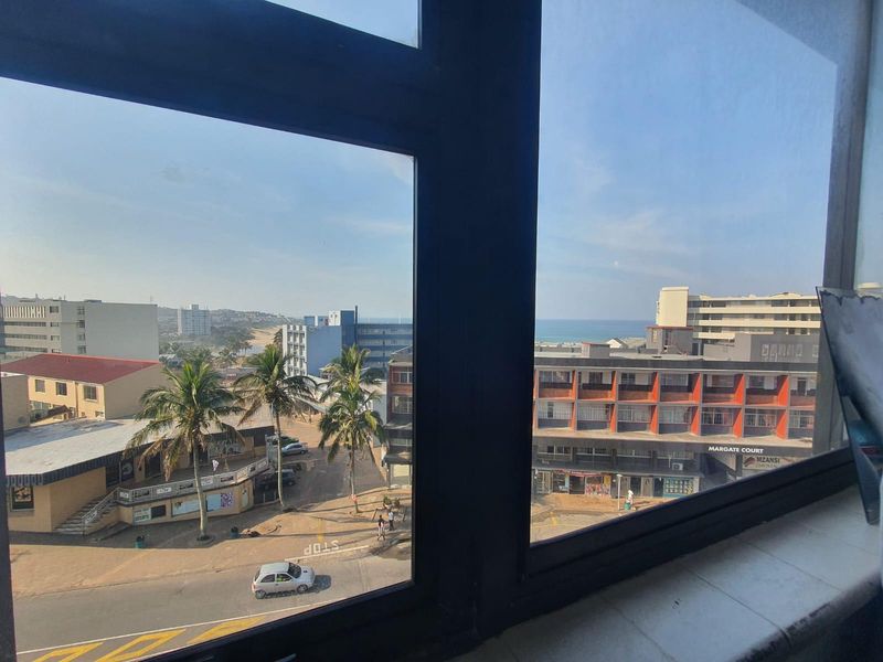 An elevated urban view looking out over the surrounding neighbourhood and coastline from an apartment window.
