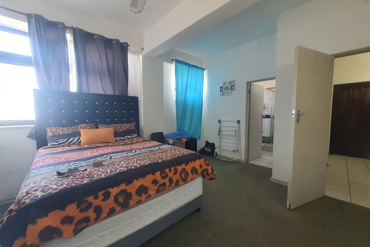 Spacious bedroom featuring a ceiling fan, tiled flooring, and direct access to an en-suite bathroom.