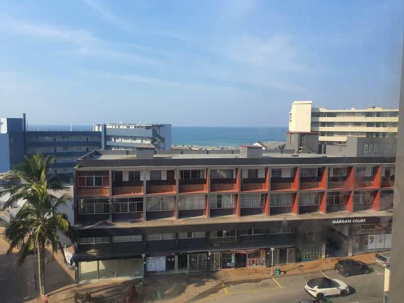An elevated view overlooking a coastal urban area with multi-story apartment buildings and a glimpse of the ocean in the background.