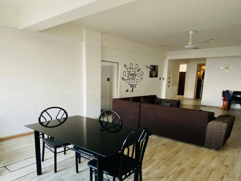Spacious open-plan living and dining area featuring light-toned laminate flooring and a ceiling fan, offering a versatile layout for modern apartment living.