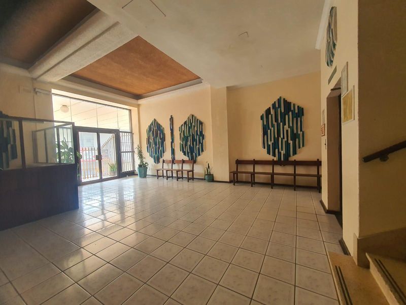 Spacious apartment building entrance lobby featuring tiled flooring, recessed ceiling detail, and glass entrance doors leading to the exterior.