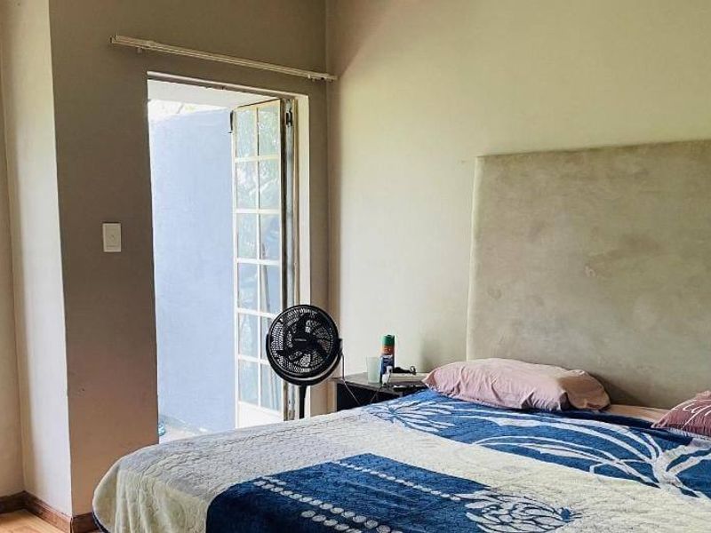 A bedroom featuring a large headboard, natural light from a casement window, and direct access to an outdoor area through french doors.